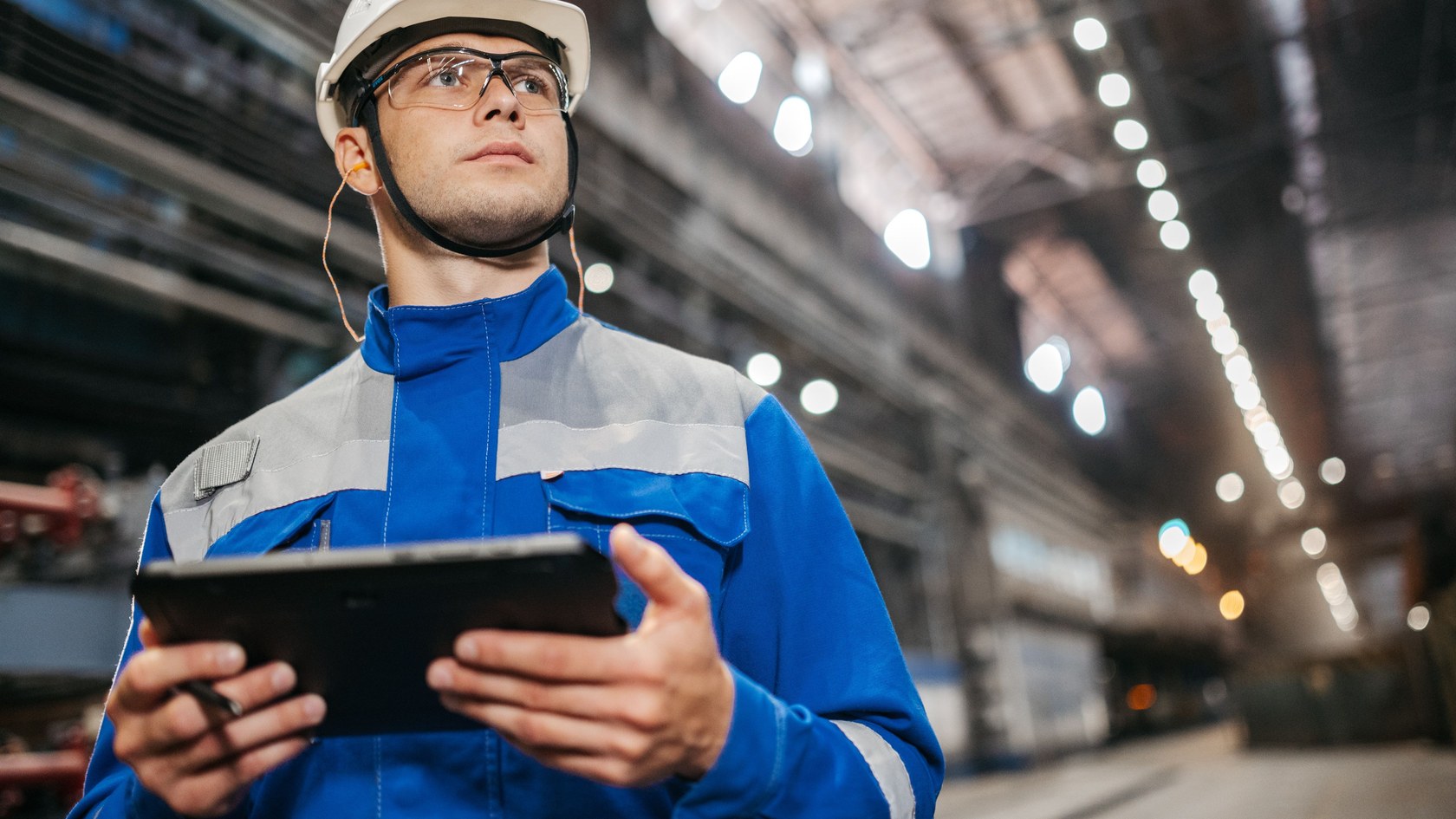 Industrial worker wearing a hard hat and using a tablet in a factory