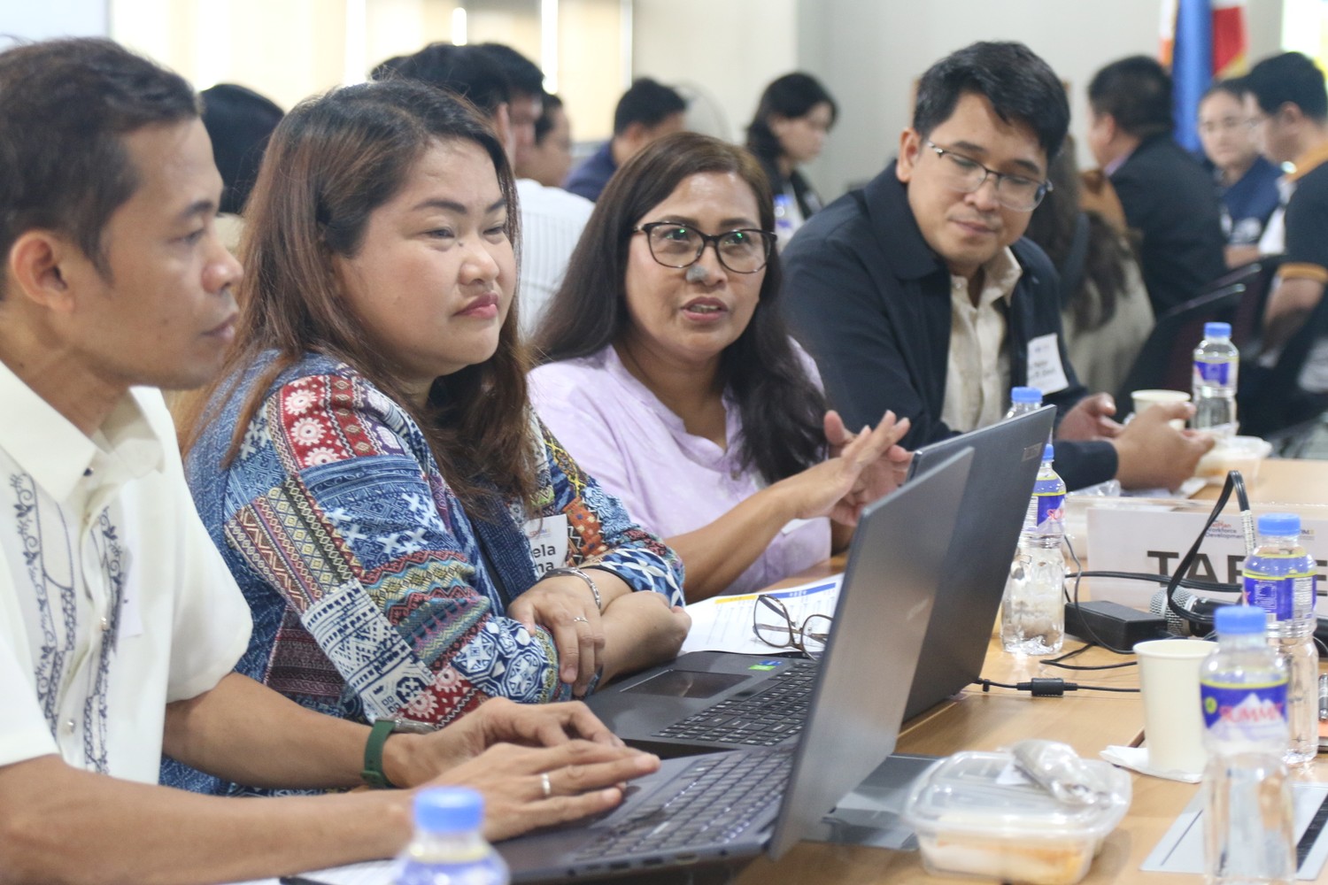 Workshop participants collaborate around a table with laptops