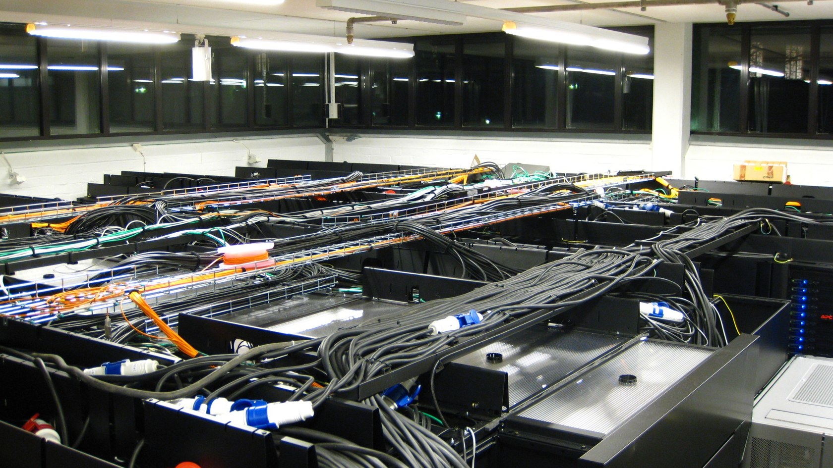 Server room with rows of computers, power equipment and network cables